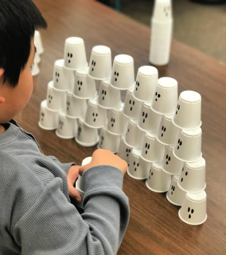 A student is stacking cups that are decorated as ghosts.
