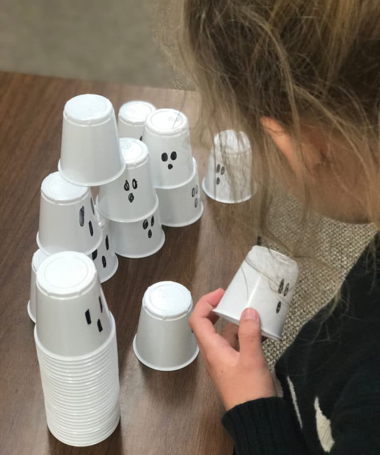 A student is stacking cups decorated as ghosts.