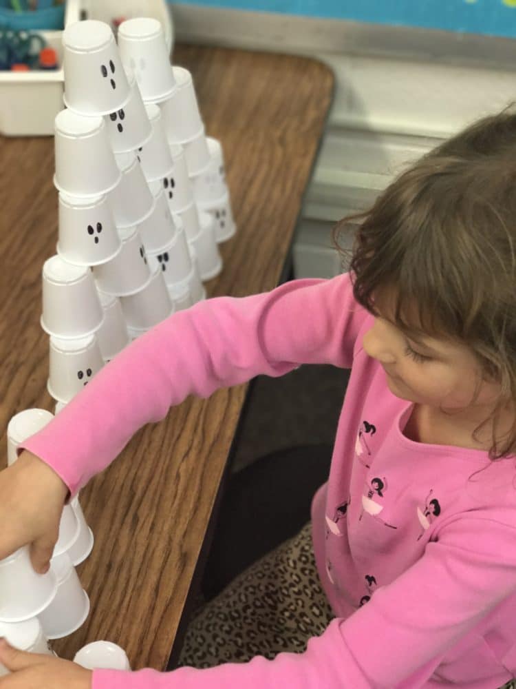 A student is stacking cups that are decorated as ghosts.