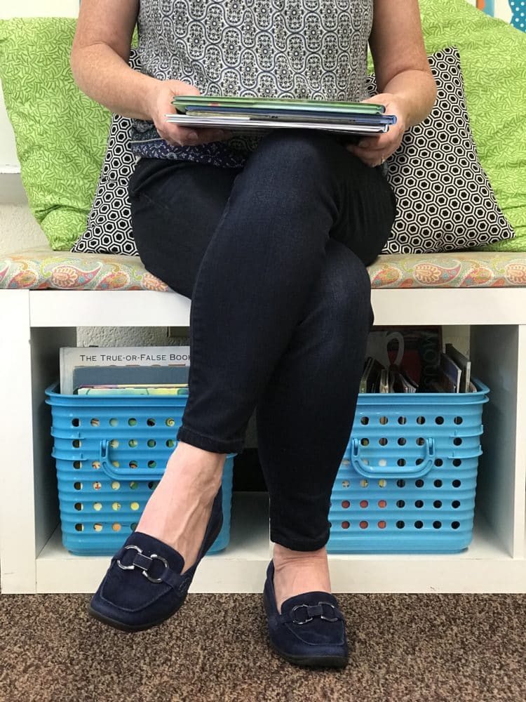 Teacher sitting with books wearing EasySpirit loafers.