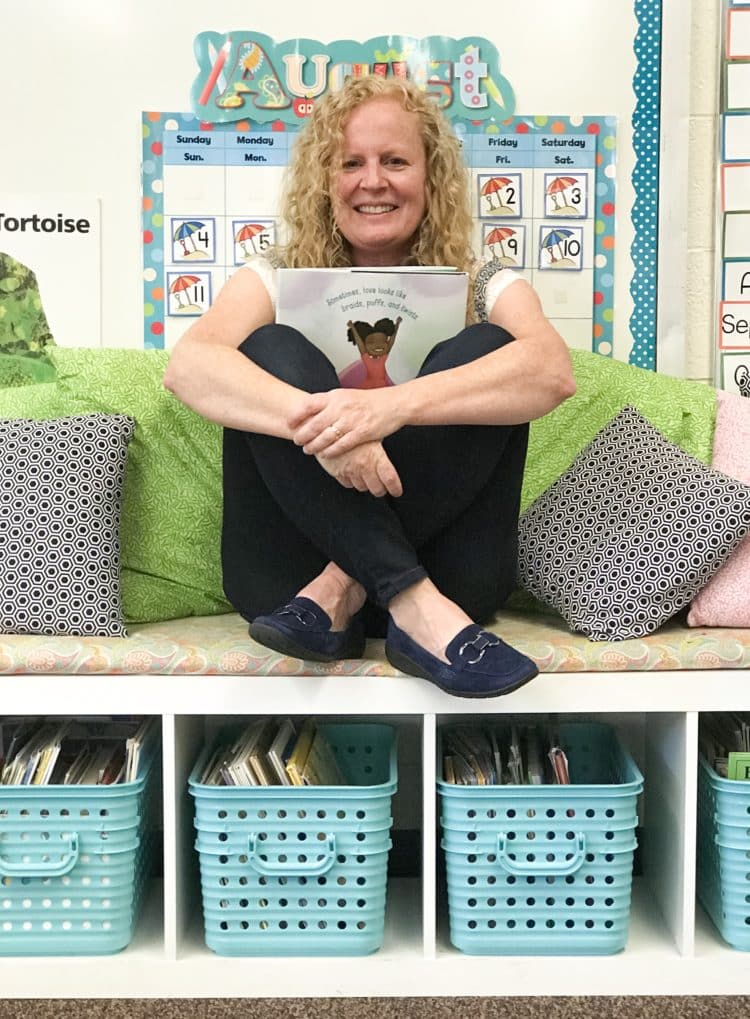 Teacher sitting holding books and wearing EasySpirit loafers.